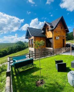uma casa de madeira com um banco e uma árvore em LUX PINE house em Zlatibor