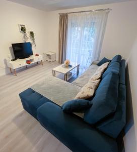 um sofá azul numa sala de estar com uma televisão em Apartmani Danica em Orebić