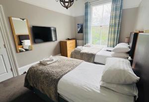 a hotel room with two beds and a television at Hedley House Hotel & Apartments in York