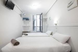 2 łóżka w niewielkim, białym pokoju z oknem w obiekcie Pensión Santa Clara w mieście San Sebastián