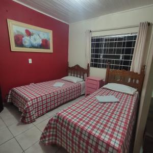 two beds in a room with red walls at Pousada Sonho in Apucarana