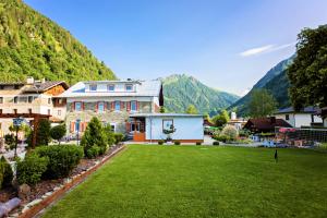dom z trawnikiem przed górą w obiekcie IMBACHHORN Pension in den Alpen w mieście Fusch an der Großglocknerstraße