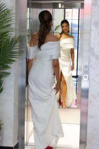 uma mulher num vestido branco a olhar para um espelho em Baba's Hotel & Spa em Dobra Voda