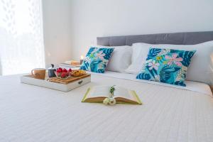 a bed with a book and a tray of fruit on it at Rossini Home Pesaro vicino al Teatro Rossini by Yohome in Pesaro