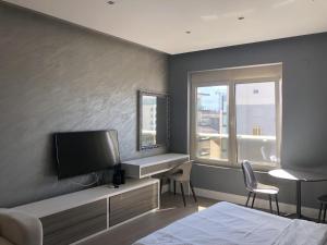 um quarto com uma cama, uma televisão e uma janela em Stylish modern studio in Budva with a sea view em Budva