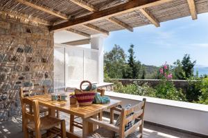 a patio with a wooden table and chairs and a large window at Blue Vista Double Apartment in Skala