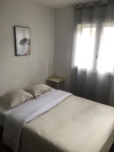 Maison du bonheur في فيليرز سور مارن: غرفة نوم بسرير أبيض مع نافذة +صورتان