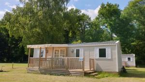 una casetta in un campo con alberi sullo sfondo di Camping La Colline - Maeva a Virton