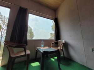 ランズドーンにあるRohini Village Homestayの窓のある小さな部屋で、テーブルと椅子2脚が備わります。