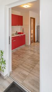 una cucina con armadi rossi e pavimenti in legno di Studio apartment a Nin