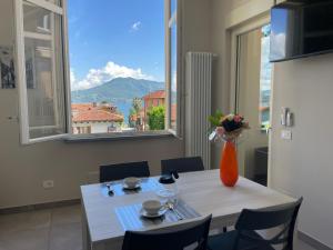 una mesa de comedor con un jarrón de flores y una ventana en Appartamento Aurora, en Cannero Riviera