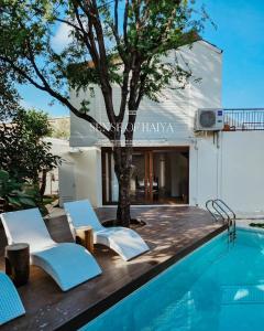 una piscina con sillas y un árbol junto a una casa en Sense of Haiya, en Chiang Mai