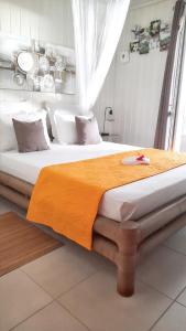 una camera da letto con un grande letto con una coperta arancione di Bungalow de 2 chambres a Bouillante a 150 m de la plage avec terrasse amenagee et wifi a Mathurin Noël