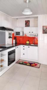 una cucina con armadi bianchi e pareti rosse di Bungalow de 2 chambres a Bouillante a 150 m de la plage avec terrasse amenagee et wifi a Mathurin Noël