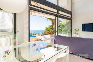 een kamer met een glazen tafel en uitzicht op de oceaan bij Super Villa Oasis Fab Sea and Sitges View with Private Pool and Air Conditioning in Sitges