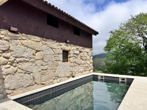 a house with a swimming pool next to a stone wall at Chalet con piscina Gondomar in Gondomar