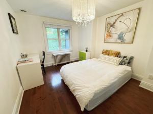 a bedroom with a white bed and a chandelier at A bright and tidy room in midtown near subway in Toronto
