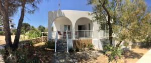 een klein wit huis met een trap in een tuin bij Rita's Beachfront House in Kampos Paros
