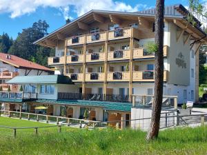 ein großes Gebäude mit Balkonen und einem Baum in der Unterkunft Das Aparthotel Olympia Tirol in Seefeld in Tirol