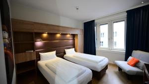 a hotel room with two beds and a chair at Motel Plus Berlin in Berlin