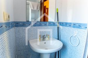 ein weißes Waschbecken in einem blau gefliesten Bad in der Unterkunft Apto Niemeyer - Avilés centro in Avilés