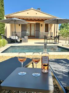 zwei Gläser Wein auf dem Tisch mit einer Flasche Wein in der Unterkunft Les Lauriers Blancs, villa avec piscine in LʼIsle-sur-la-Sorgue