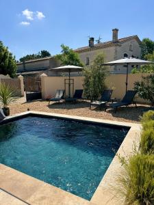 einen Pool mit Stühlen und Sonnenschirmen im Hof in der Unterkunft Les Lauriers Blancs, villa avec piscine in LʼIsle-sur-la-Sorgue