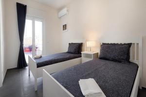 zwei Betten in einem weißen Zimmer mit Fenster in der Unterkunft Casa Suli Beachfront in Marina di Ragusa