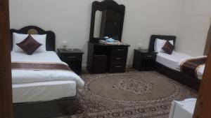 a bedroom with two beds and a mirror and a rug at العييري للشقق المفروشة االنعيريه 1 in Al Nairyah