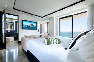 a bedroom with a large white bed and large windows at BLESS Hotel Ibiza - The Leading Hotels of The World in Es Cana