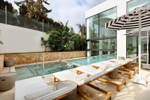 a house with a pool and lounge chairs at BLESS Hotel Ibiza - The Leading Hotels of The World in Es Cana