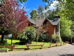 ein Blockhaus mit einem Zaun davor in der Unterkunft Cuncumen Casa de Montaña in Villa La Angostura