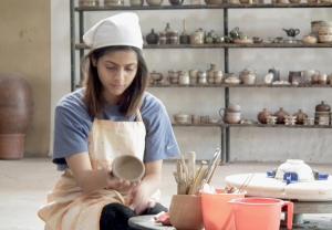 a woman in a chefs hat is working in a pottery at Clayfingers Art Cottage in Trichūr