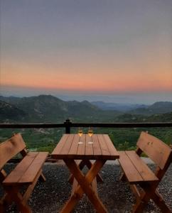 a wooden picnic table with two glasses of wine at Camp Oaza,Lipa in Cetinje
