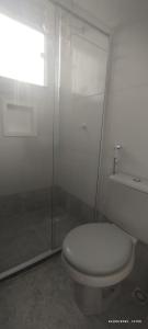 ein weißes Bad mit einem WC und einer Dusche in der Unterkunft Guest House Renascer K&W in Cabo Frio