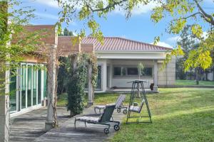 una casa con 2 sillas de jardín y un columpio en 4 bedrooms villa with indoor pool jacuzzi and enclosed garden at Santo Tirso, en Santo Tirso
