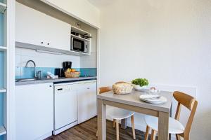 una pequeña cocina con mesa y sillas en una habitación en Residence Pierre & Vacances Les Balcons de Collioure, en Collioure