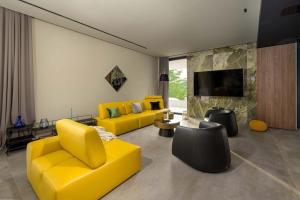 a living room with two yellow chairs and a tv at Villa She Luxury in Boškari