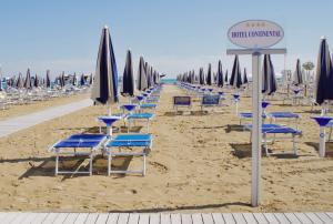 una fila di sedie e ombrelloni in spiaggia di Continental B&B City Hotel a Bibione