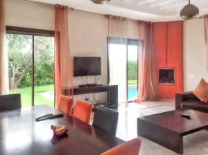 uma sala de estar com uma mesa e cadeiras laranja em 3 bedrooms villa with private pool and enclosed garden at Marrakech em Douar bel Rhanodour
