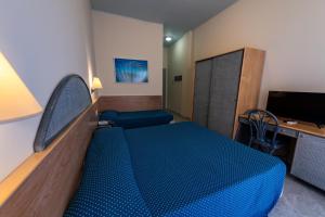 um quarto com uma cama azul e uma secretária em Hotel Baia Turchese em Lampedusa