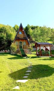 uma cabana de madeira com um gazebo num campo em Vilat Pllumaj em Gropat e Selcës