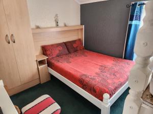a small bedroom with a bed with a red blanket at Glen Allan in Blackpool