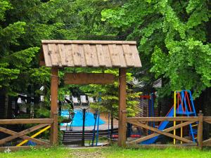 un parco giochi con struttura in legno accanto a una piscina di Gostynniy Dvir Коттеджи a Myhove