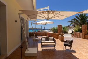 um pátio com uma mesa, cadeiras e um guarda-sol em Hotel Baia Turchese em Lampedusa