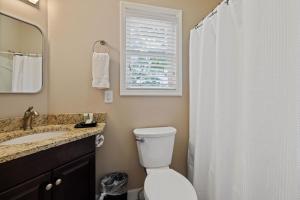 ein Badezimmer mit Toilette, Waschbecken und Spiegel in der Unterkunft Little Bear Cottage is located only a half-mile away from downtown Gatlinburg! in Gatlinburg + 20 Fotos