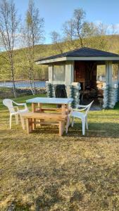 uma mesa de piquenique e duas cadeiras em frente a uma cabana em Vetsikon Leirintämökit em Utsjoki