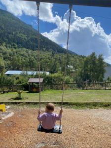 un niño sentado en un columpio en un parque infantil en Chalet chaleureux l’hospitalet près l’andorre ., en L'Hospitalet-près-l'Andorre