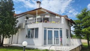 图伦诺沃Guest house FantasY的白色的房子,阳台配有椅子