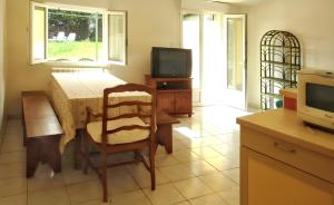 eine Küche mit einem Tisch, einem Stuhl und einem TV in der Unterkunft Maison de 2 chambres avec jardin clos et wifi a Berriac in Berriac